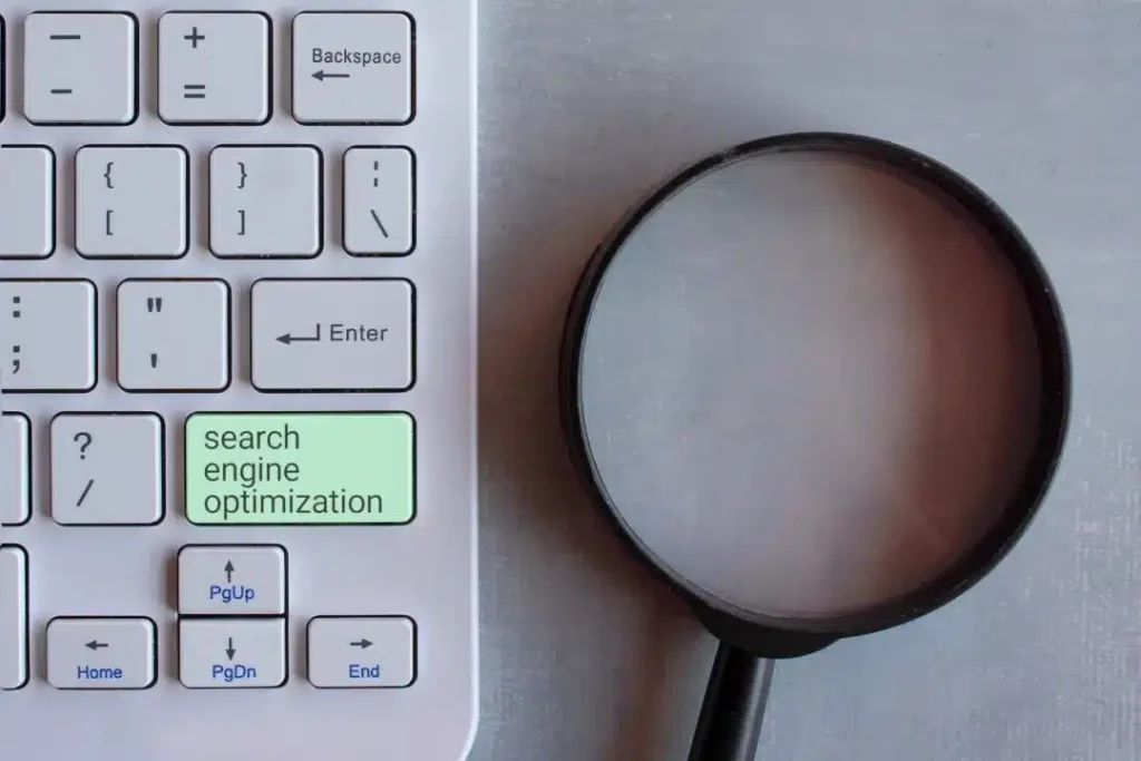 A close-up view of a magnifying glass adjacent to a keyboard, symbolizing focus and precision in digital tasks.