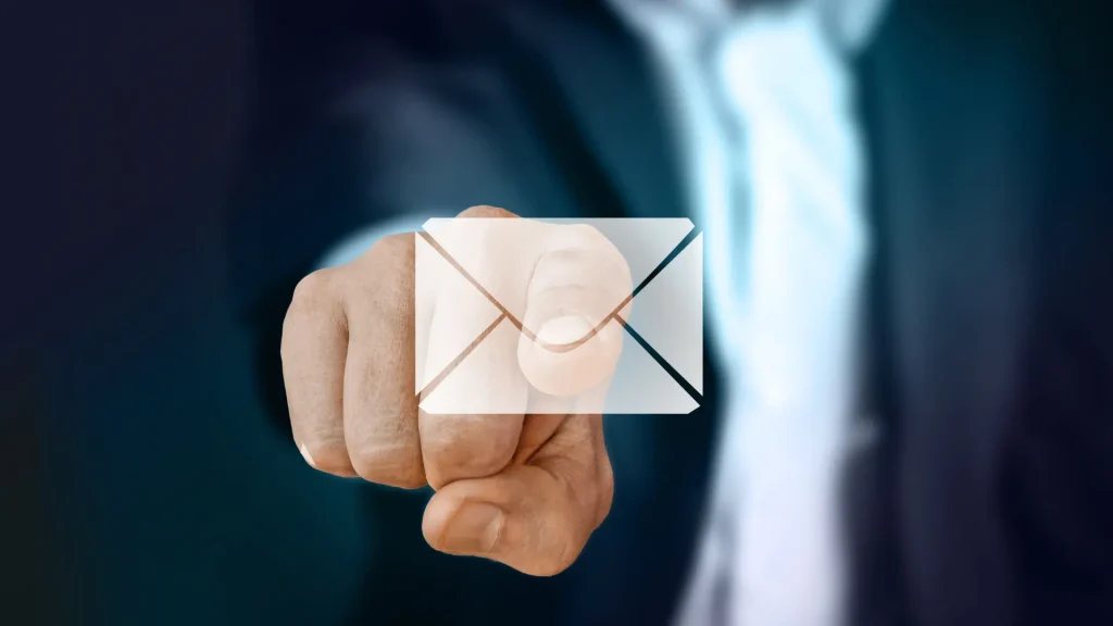 Business person pointing at a transparent email icon, representing email marketing automation and lead nurturing.