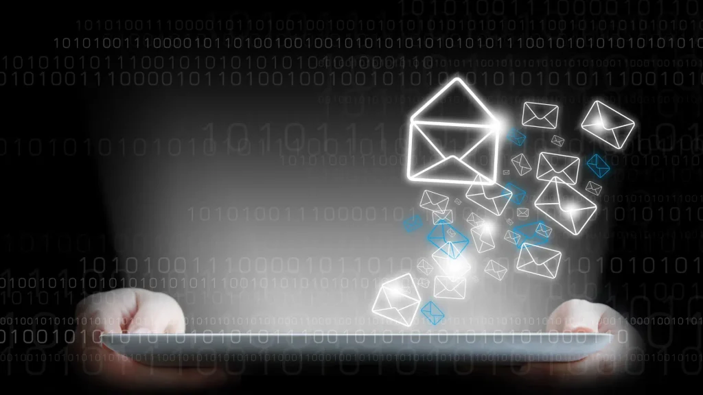 Hands holding a tablet with glowing email icons emerging, representing email campaigns and marketing automation.