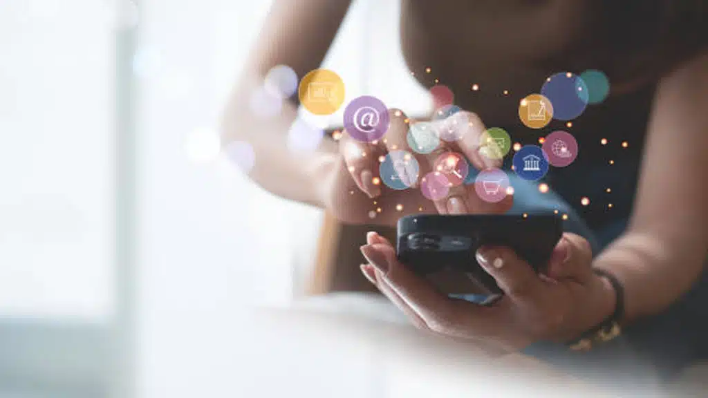 A person using a smartphone, surrounded by various glowing icons such as email, cart, and message notifications, symbolizing the best practices for effective SMS marketing.
