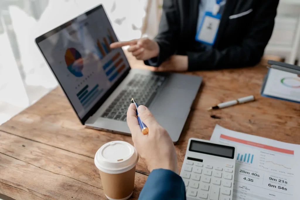 Business professionals collaborating on a laptop at a desk, focused on their work and engaged in discussion.