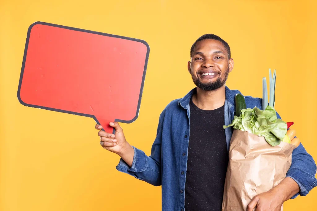 A man with a shopping bag stands, accompanied by a speech bubble, indicating he is engaged in a discussion or sharing ideas.