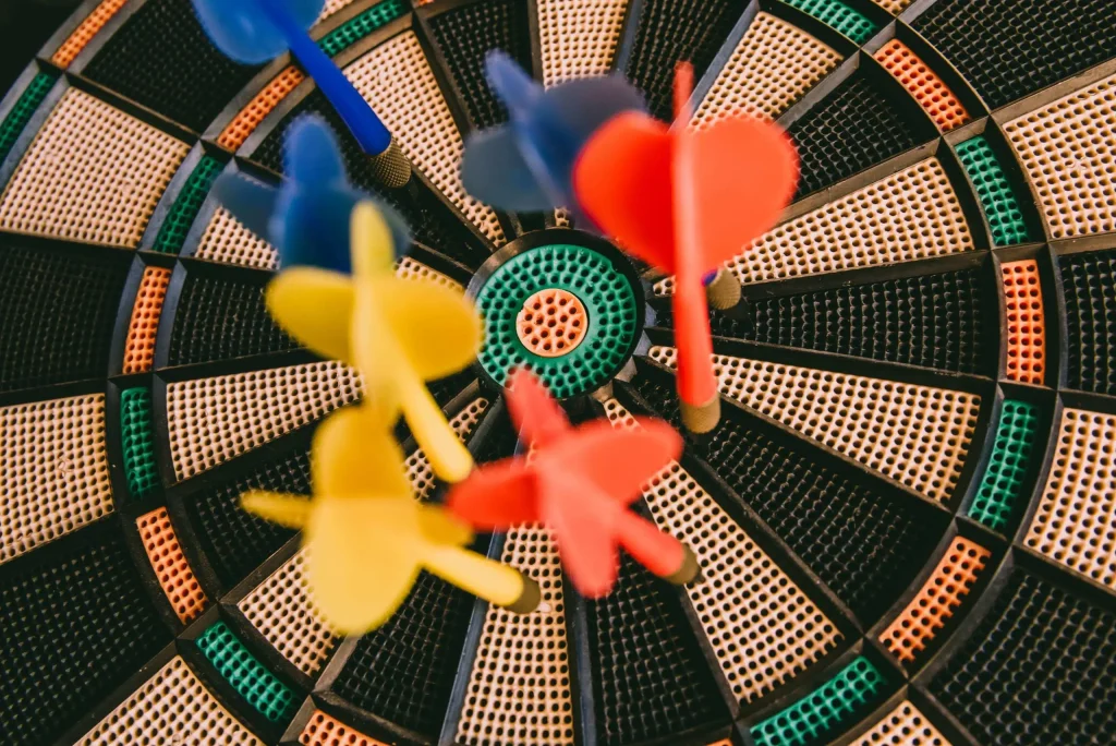 The image features a dart striking the center of a dartboard, symbolizing precision and skill in the game.