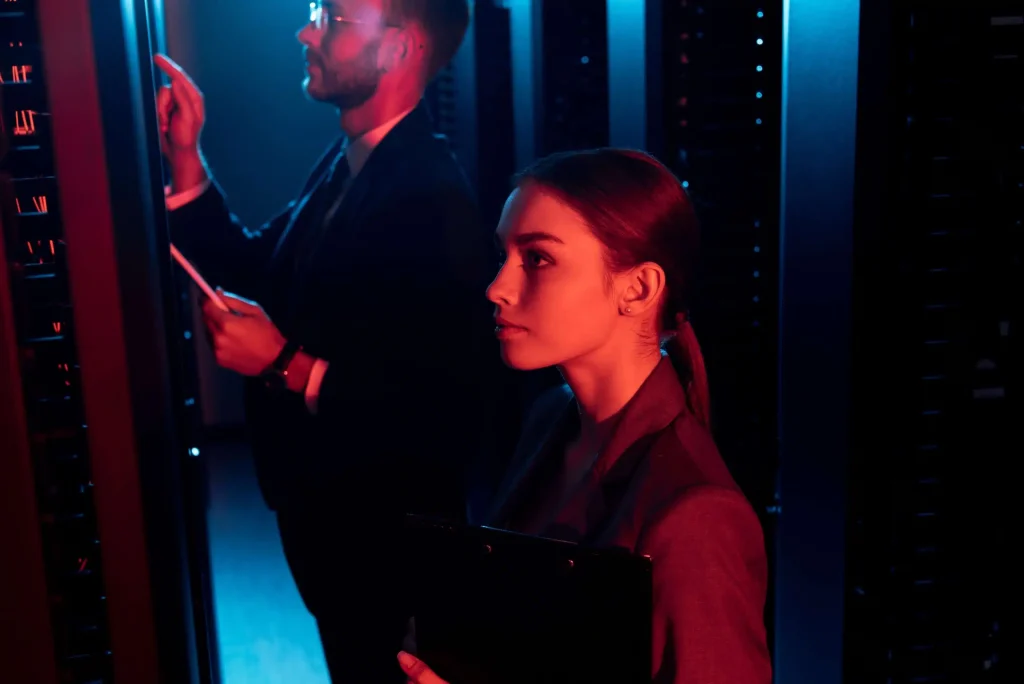 Two people positioned in front of server racks within a data center, highlighting the infrastructure of data management.